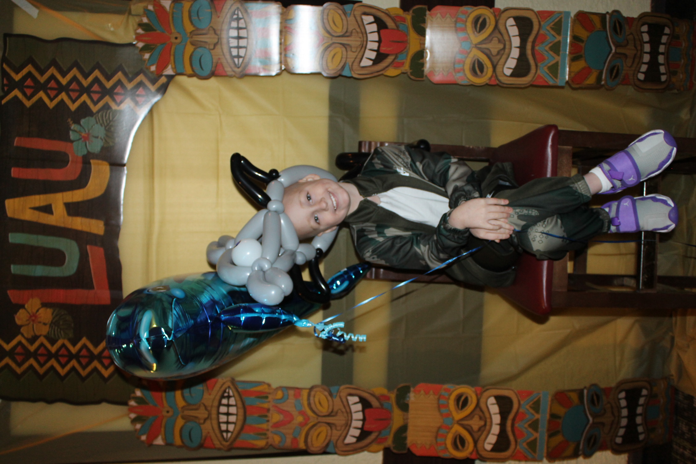 Elias sitting with Shark and Dolphin Balloons